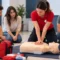 Instructora realizando una demostración de reanimación cardiopulmonar (RCP) con un maniquí durante un curso de primeros auxilios en Gijón.